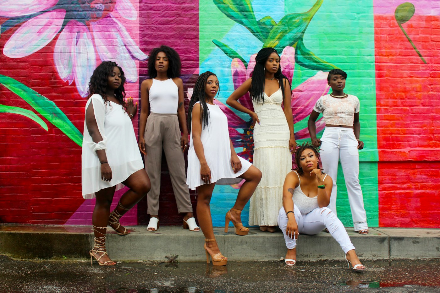 Six women in white against a colorful mural